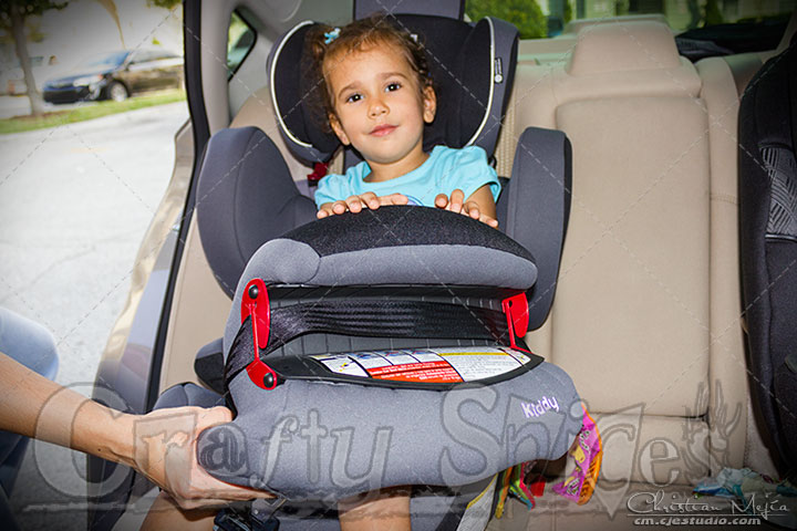 4 year old on the Kiddy World Plus Car Seat, putting the shield